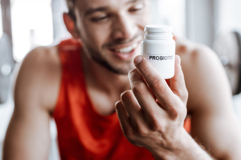 homem sorrindo olhando para pote de remedio