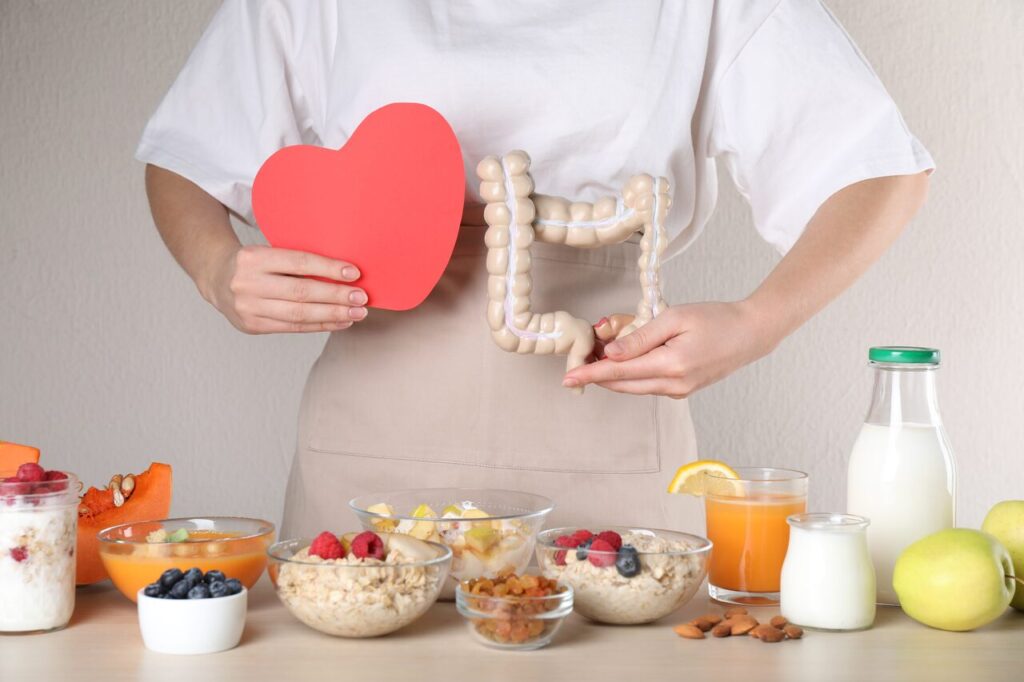 Mulher segurando modelo do intestino e alimentos saudáveis relacionados à digestão lenta e saúde intestinal.